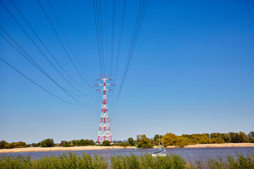 Rot-weiße Strommasten stehen an der Elbe. Deutschland, Hamburg, rot-weiße Strommasten unter blauem Himmel