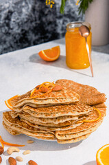 Crepes or Blinis stacked on a plate with nuts and orange jam. Spring breakfast.