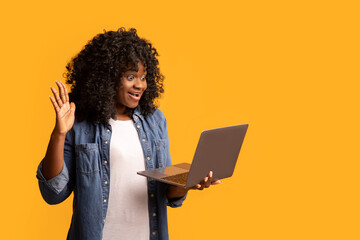 Cute black lady waving at laptop screen, having video call