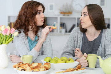 Two smiling female friends sitting at table