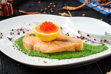 Gourmet cooked salmon fillet steak with red caviar and cucumber sauce