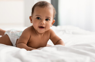 Cute adorable little African American kid lying on bed