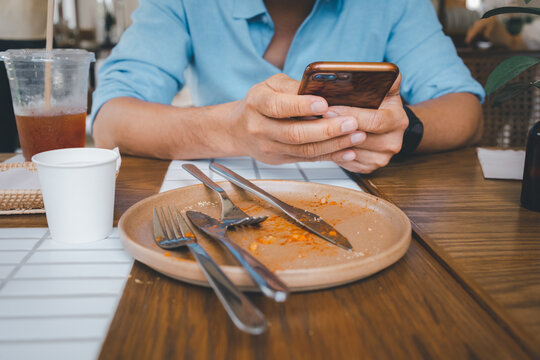 closeup man hand using smartphone after meal