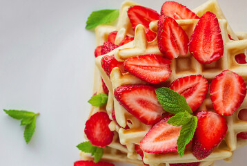 Belgian waffles with fresh strawberry and mint on white background. Top view. Close up. Copy space