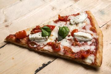 Dettaglio di uno spicchio di Pizza  al pomodoro e mozzarella sopra un tavolo di legno