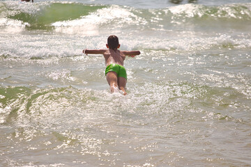 child swims in the sea waves on the beach