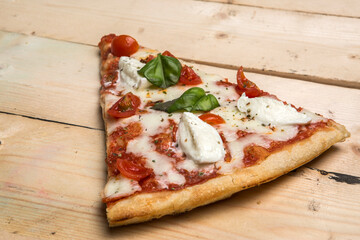 Dettaglio di uno spicchio di Pizza  al pomodoro e mozzarella sopra un tavolo di legno