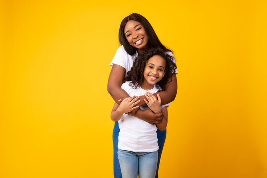 African American Woman Hugging Her Smiling Daughter From The Back