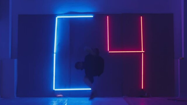 Person in windbreaker and red cap dancing to breakdance on C-4 neon symbol. red and blue  neon background . Flickering neon background . man dancing to breakdance in night club