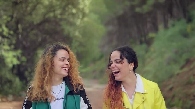 Dos hermanas gemelas riendo y charlando con complicidad en un camino del bosque