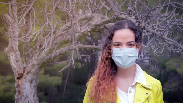 mujer con mascarilla delante de las ramas de un &aacute;rbol en un bosque