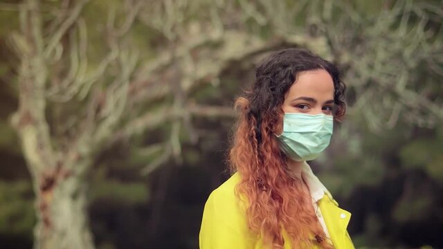mujer con mascarilla delante de las ramas de un &aacute;rbol en un bosque