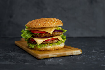 large burger with cutlet, tomato, mayonnaise, lettuce, onion rings. fast food, american food 