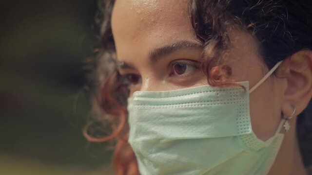 Primer plano de los ojos de una Mujer Joven con mascarilla quir&uacute;rgica en el bosque 