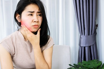 Asian woman suffering from toothache problem hand holding face, painful gums