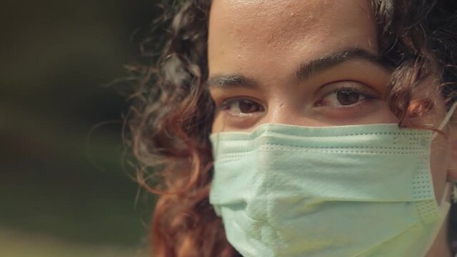 Primer plano de los ojos de una Mujer Joven con mascarilla quir&uacute;rgica en el bosque 
