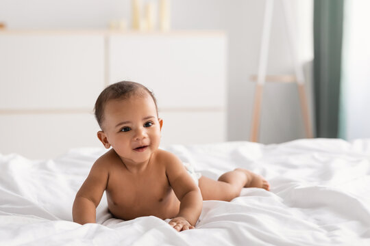 Cute little African American infant lying on bed