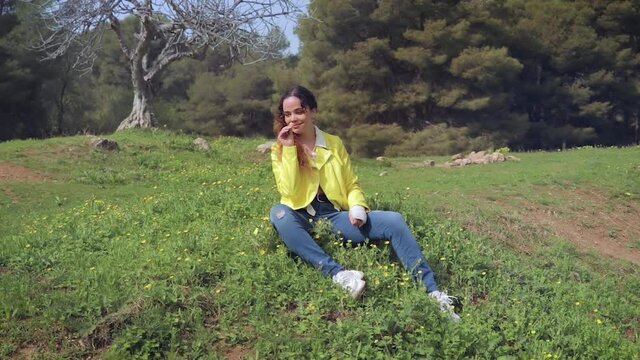 Mujer con brazo escayolado juega con las flores amarillas en un prado, quitando los p&eacute;talos 
