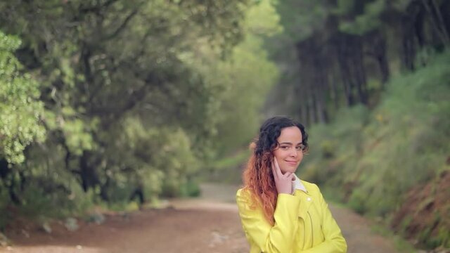 mujer sonriendo en un camino en el bosque verde cubierto por &aacute;rboles