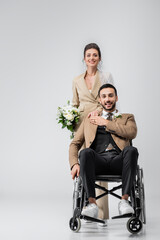 Plakat disabled muslim man and happy bride with wedding bouquet smiling at camera on grey