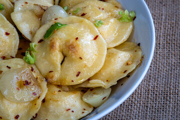 Pelmeni dumplings making process: Close up on cooked pelmeni stuffed with meat in a bowl with seasoning and onions. Gluten free recipe for traditional Russian cuisine. handmade ravioli or dumplings.