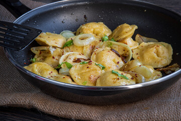 Pelmeni dumplings making process: Cooked and fried pelmeni stuffed with meat inside a pan with seasoning, onions. Gluten free recipe for traditional Russian cuisine. handmade ravioli or dumplings.