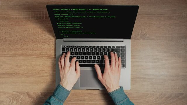 Closeup a man hands are typing commands of a laptop keyboard. A man is writing a program. The developer is coding. Code on the laptop screen. Concept of programming and development web.