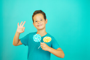 Smiling boy with lollipops in hand and okay gesture