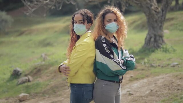 c&aacute;mara girando sobre dos hermanas gemelas de espaldas y con mascarilla, en el bosque