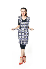 A young woman in a black dress and red shoes elegantly knots an apron of a housewife isolated on a white background