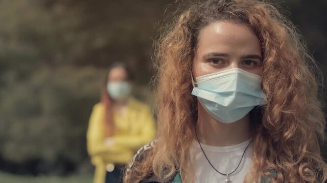 Dos hermanas gemelas pelirrojas, una detr&aacute;s de la otra, en un bosque con &aacute;rboles en el fondo