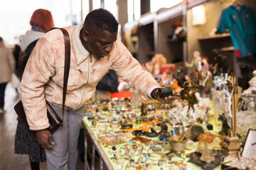 African American man chooses antiques on the flea market