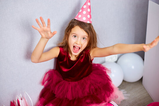 Cute, Joyful little girl in pink dress and hat play with balloons at home birthday party