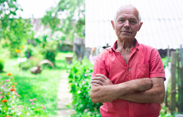 senior pensioner in red polo posing near the house in the village