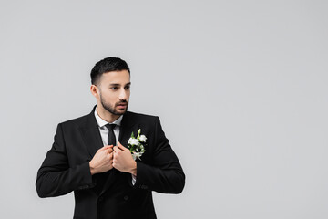 Arabian groom looking away while wearing jacket isolated on grey