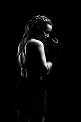 Young woman goes in for sports. She trains with boxing gloves. The photo is black and white.