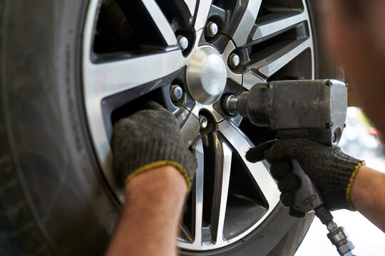 Mechanic male use air gun try to remove nut wheel for replace tires in car service