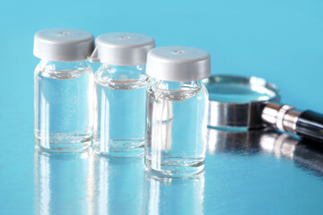  magnifying glass and bottles of covid-19 coronavirus vaccine, fake vaccine