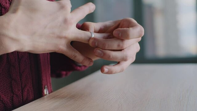 Close-up of male hands, cropped shot frustrated divorced deceived caucasian man husband takes off wedding ring puts on wooden table decides to separate, breakup marriage concept, end of relationship