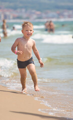Fototapeta na wymiar child swims in the sea waves on the beach