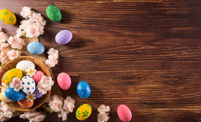 Happy easter! Colourful of Easter eggs in the nest with flower on dark wooden background. Greetings and presents for Easter Day celebrate time. Flat lay ,top view.