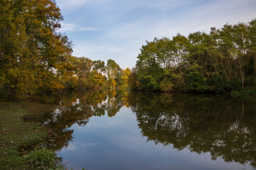 Fototapeta na wymiar Landscape by the water. Stara Dyje river near Genoa castle in Czech republic. Trees are reflected in the river. Calm water. Colorful autumn. Beautiful clouds in the sky.