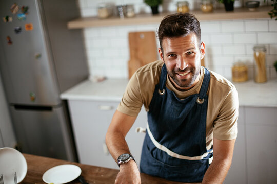 Happy smiling man preparing tasty meal. Young man cooking in the kitchen..