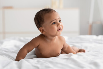 Cute little African American kid lying on bed