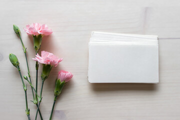 Mockup template with pink flowers and blank business cards paper on wooden background. 