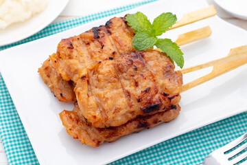 Moo ping, grilled pork skewers in Thai food style, one of popular Thai street foods, easily found in morning rush hour throughout Thailand.