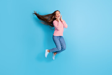 Fototapeta na wymiar Full length body size photo jumping girl amazed overjoyed touching cheeks smiling isolated vibrant blue color background