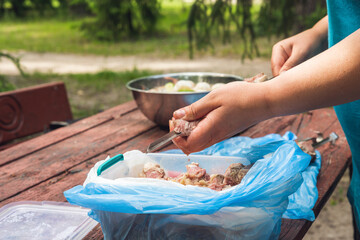 The hands of the cook string the marinated meat on a skewer for the subsequent frying of the kebab on the grill