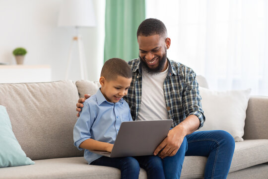 African American Father And Son Using Laptop Together At Home