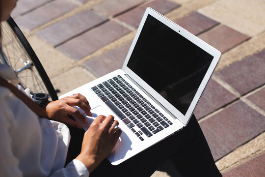 Mixed race woman sitting in park using laptop